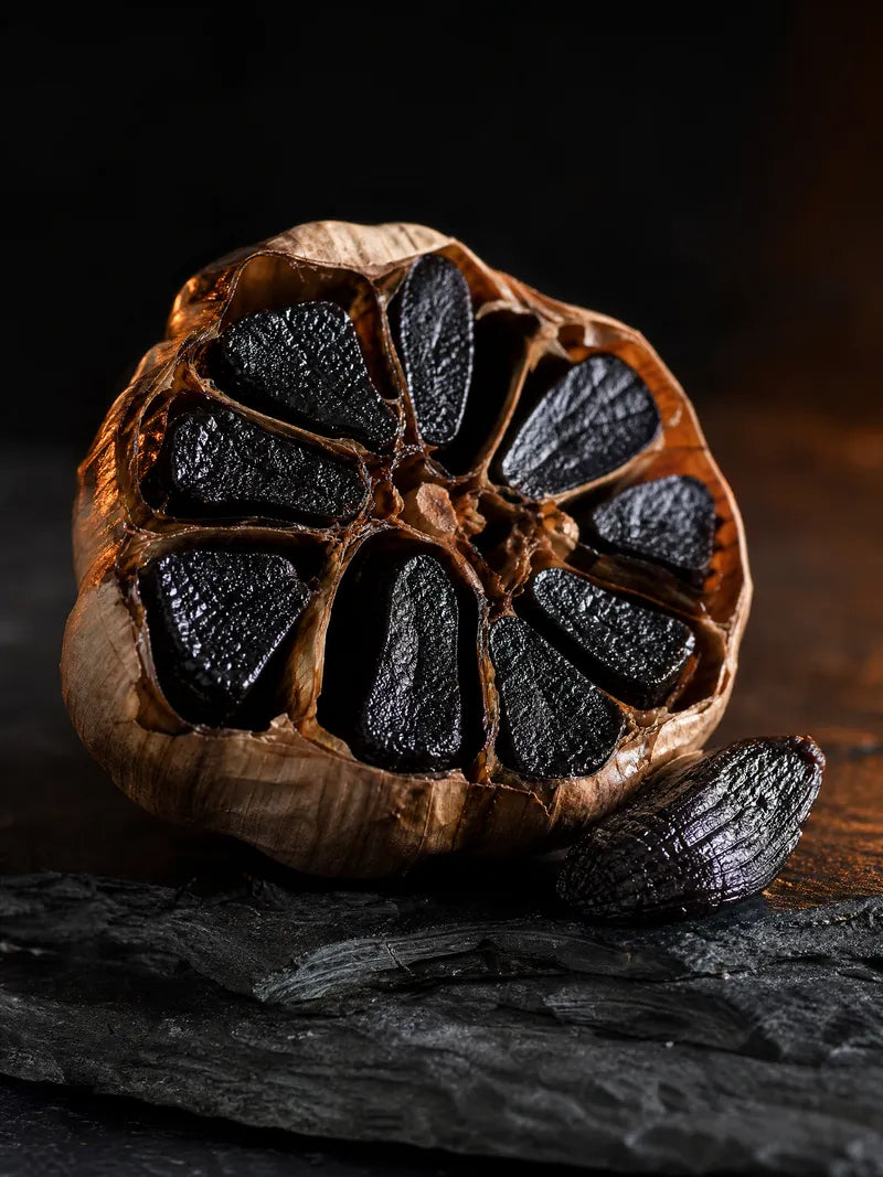 A halved black garlic bulb with glossy black cloves